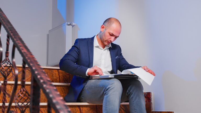 Office manager reading raport sitting on stairs