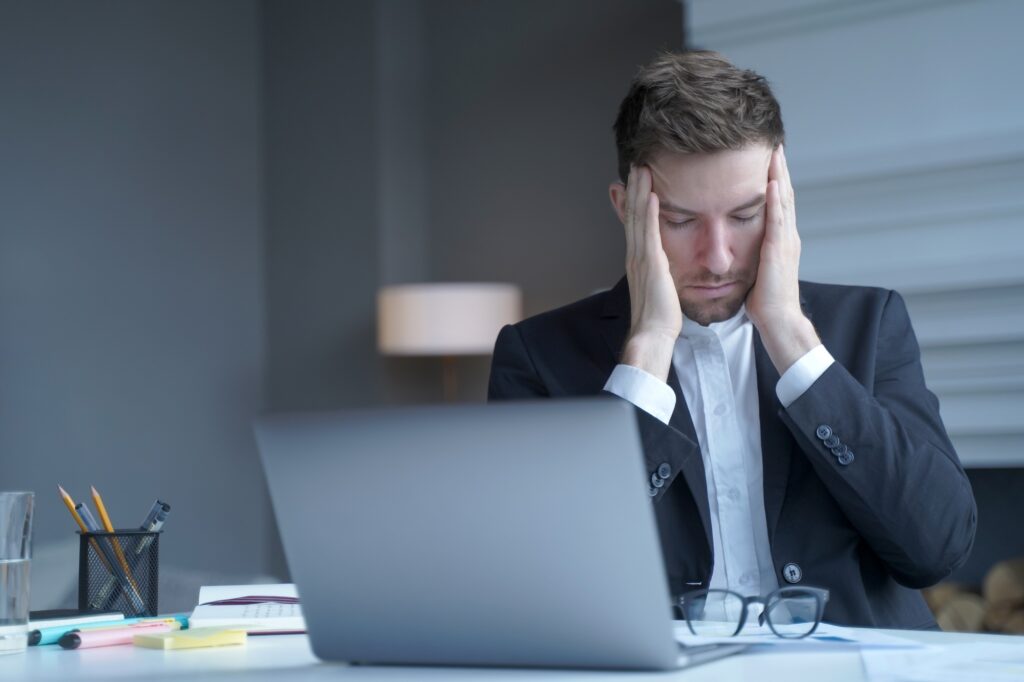 Exhausted legal consultant sitting at home office gently touches his temples with fingers